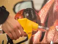 Mano che inserisce la pompa del **diesel nella benzina**. Gocce d'acqua sulla carrozzeria arancione.