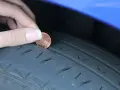 Dito si vede perché le gomme si consumano all'interno: una moneta viene inserita nel battistrada usurato di uno pneumatico.