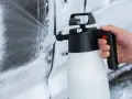 Mano che spruzza schiuma per lavare auto a casa con un erogatore.