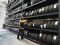 Un uomo in magazzino controlla il deposito pneumatici. Scaffali pieni di gomme, pronte per essere montate.