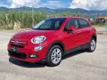 Fiat 500X rossa parcheggiata all'aperto, con montagne sullo sfondo. Controlla la pressione pneumatici per un viaggio sicuro.