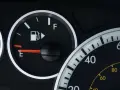 Cruscotto auto con indicatore carburante quasi vuoto, la spia pompa benzina è accesa.