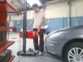 Tecnico effettua la revisione auto ibride in officina, regolando un faro con apparecchiatura specifica.