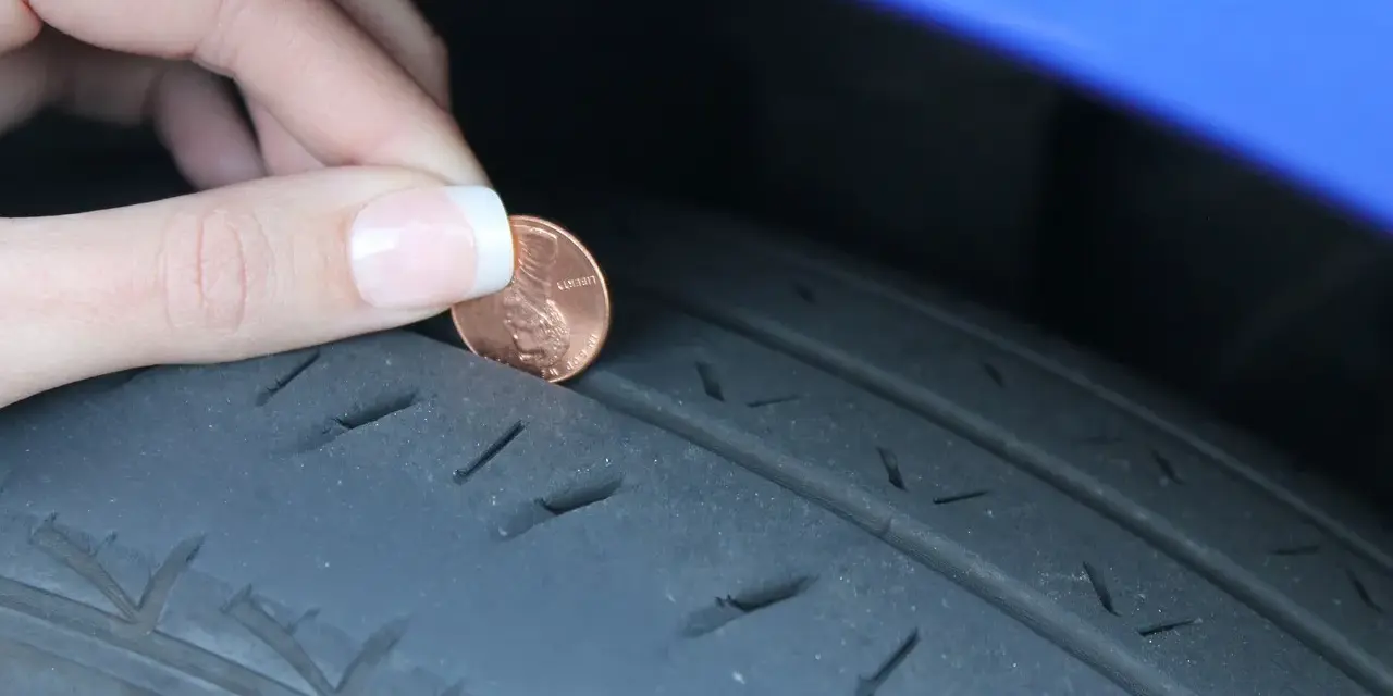 Dito si vede perché le gomme si consumano all'interno: una moneta viene inserita nel battistrada usurato di uno pneumatico.