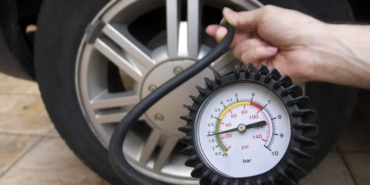 Controllo pressione pneumatici: un manometro collegato alla valvola di un'auto mostra la pressione attuale.