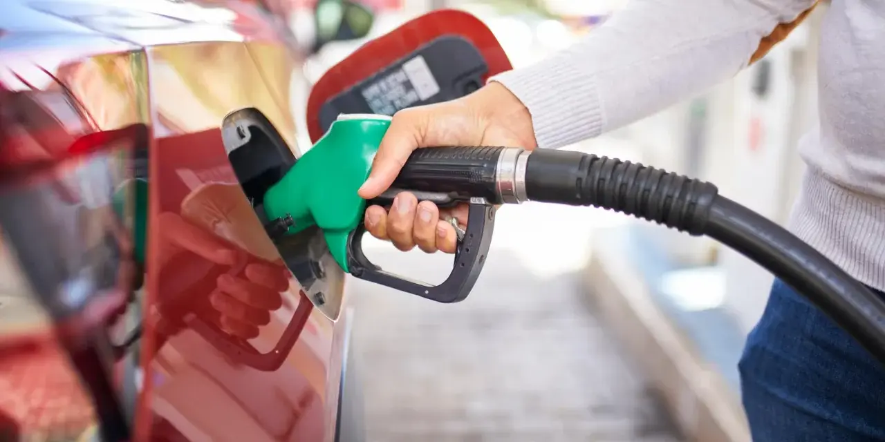 Mano che inserisce la pompa di benzina nel serbatoio di un'auto rossa. Attenzione a non mettere benzina nel diesel!