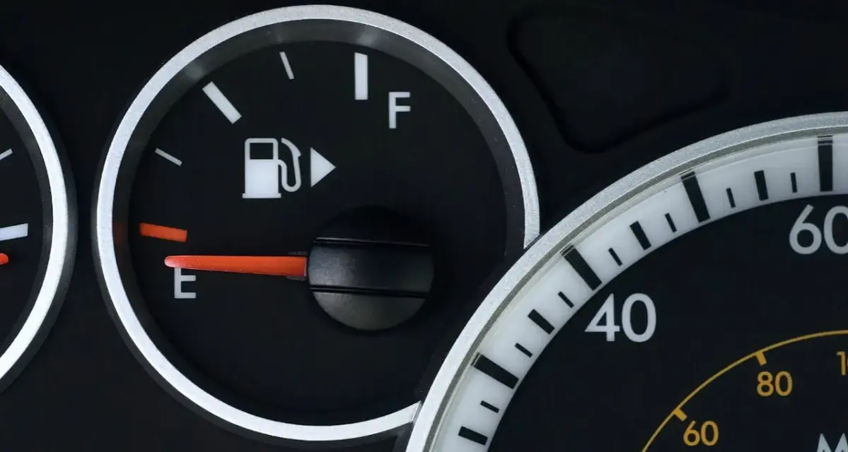 Cruscotto auto con indicatore carburante quasi vuoto, la spia pompa benzina è accesa.