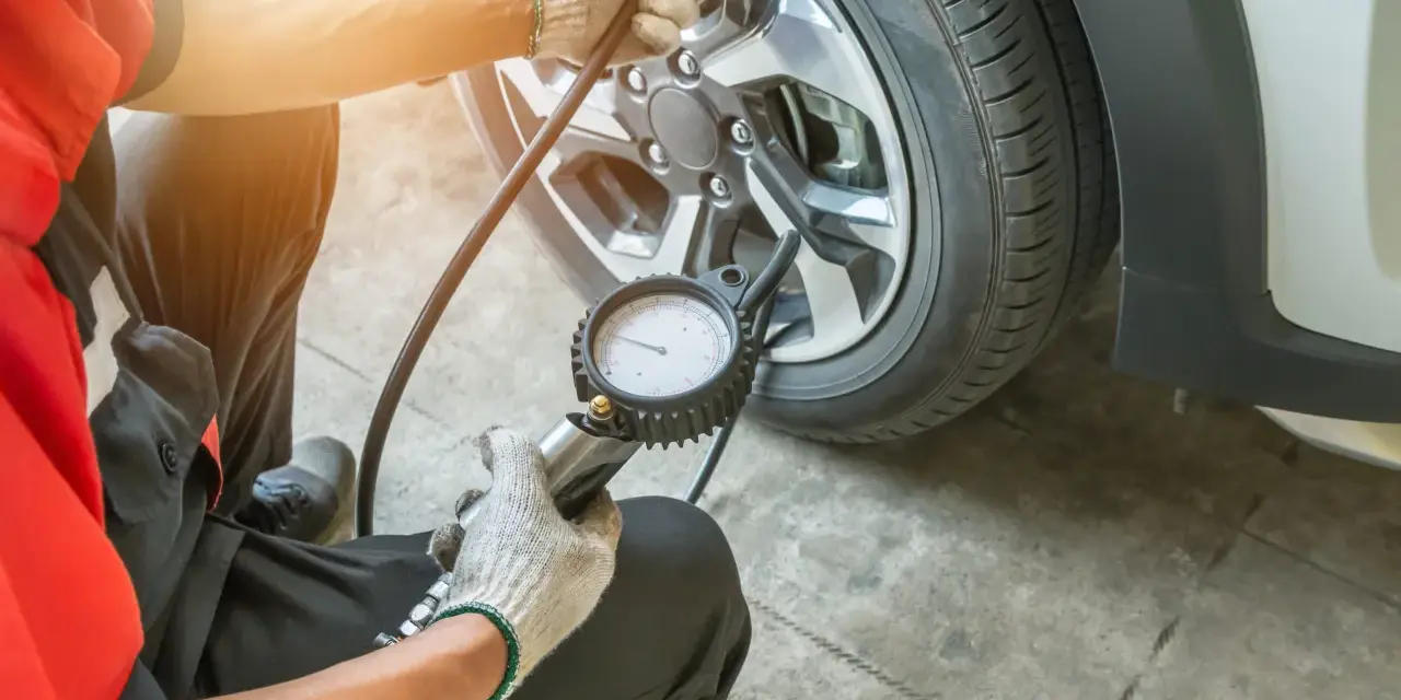 Meccanico controlla la pressione gomme, puntando a 3 bar per una guida sicura.