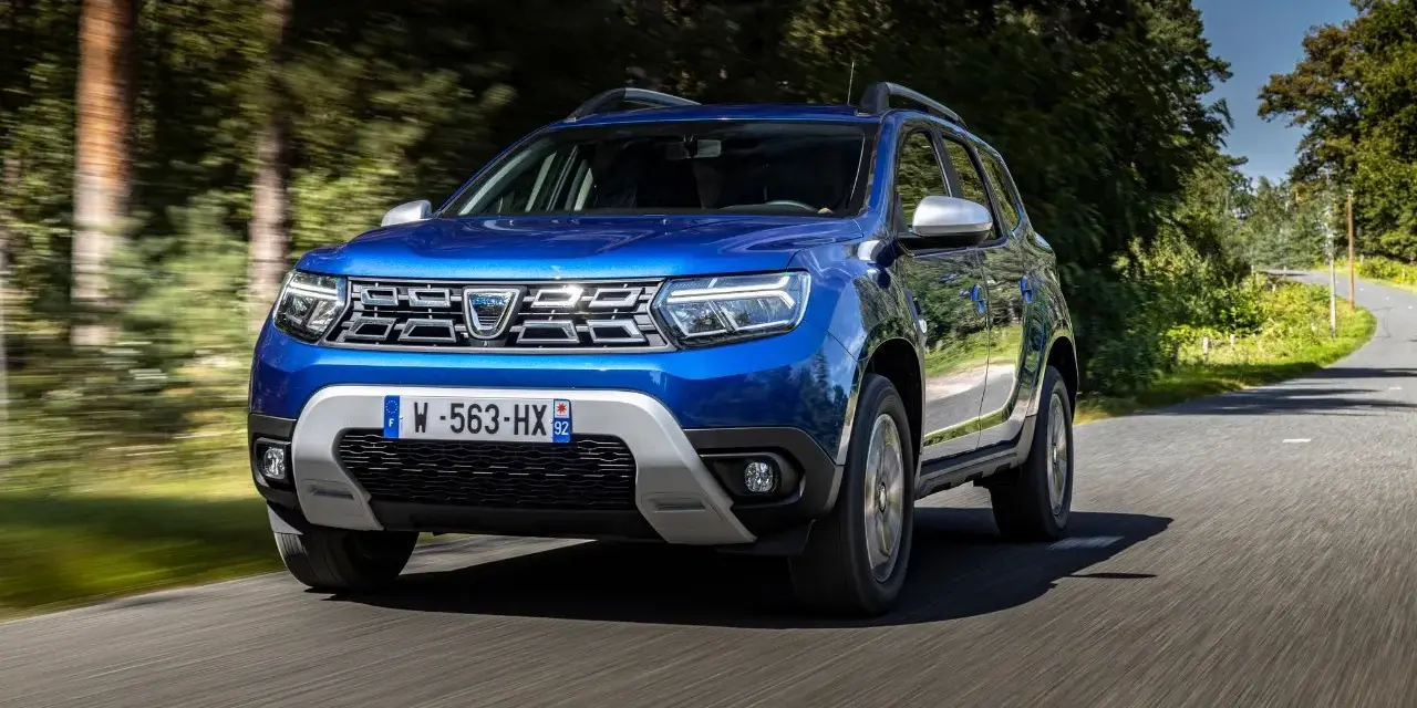 Dacia Duster blu in movimento su strada panoramica. Informazioni sul costo tagliando Dacia Duster.