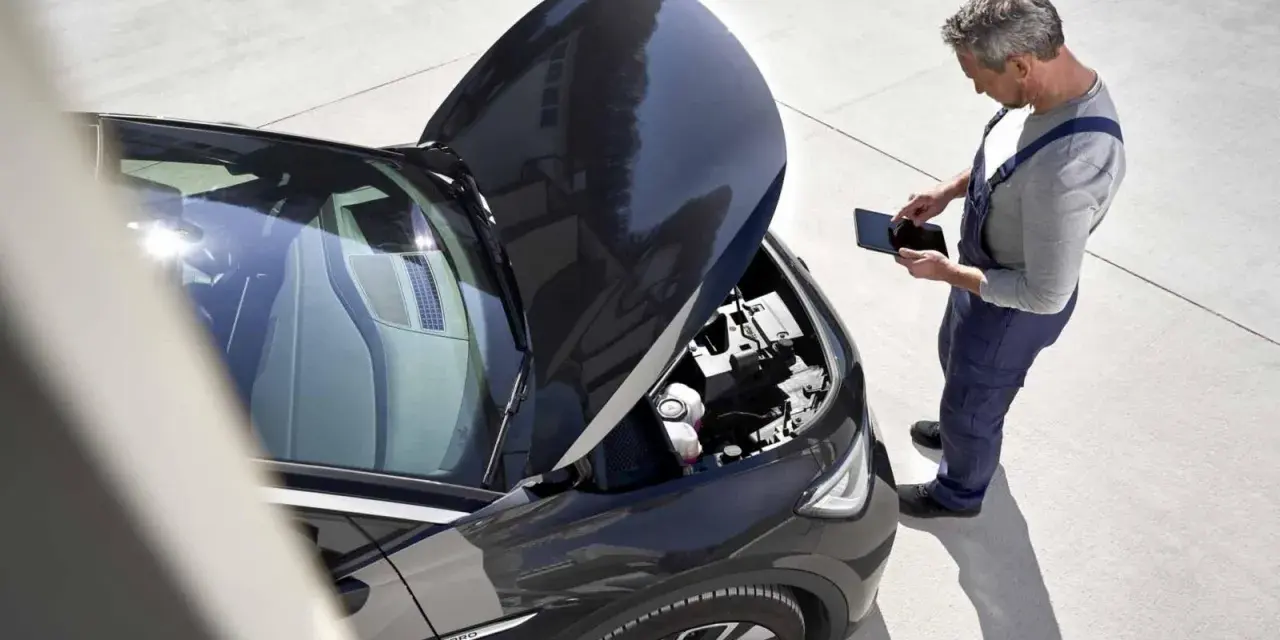 Meccanico con tablet controlla il motore dell'auto. Scopri quanto costa un tagliando auto per la tua vettura.
