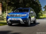 Dacia Duster blu in movimento su strada panoramica. Informazioni sul costo tagliando Dacia Duster.
