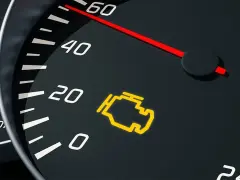 Cruscotto auto con spia olio arancione accesa. L'indicatore del motore è illuminato, segnalando un problema.