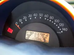 Cruscotto auto con tachimetro e spia del freno di stazionamento accesa. Chilometraggio 122599 km.