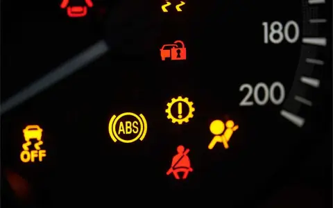 Cruscotto auto con spia ABS accesa fissa, insieme ad altre spie di avaria.