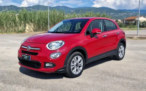 Fiat 500X rossa parcheggiata all'aperto, con montagne sullo sfondo. Controlla la pressione pneumatici per un viaggio sicuro.