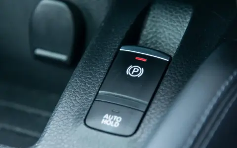 Pulsante freno a mano elettronico con spia rossa accesa e scritta "AUTO HOLD".