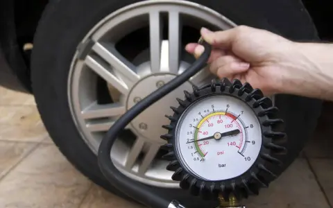 Controllo pressione pneumatici: un manometro collegato alla valvola di un'auto mostra la pressione attuale.