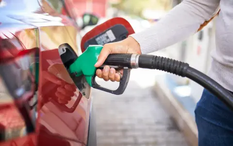 Mano che inserisce la pompa di benzina nel serbatoio di un'auto rossa. Attenzione a non mettere benzina nel diesel!
