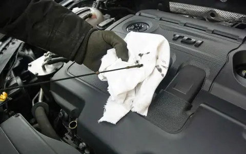 Controllo livello olio motore. Macchie scure sul panno indicano possibili coppa dell'olio rotta o perdite.