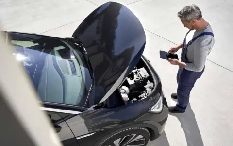 Meccanico con tablet controlla il motore dell'auto. Scopri quanto costa un tagliando auto per la tua vettura.