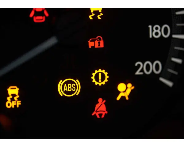 Cruscotto auto con spia ABS e freno a mano accese, insieme ad altre spie di avaria.