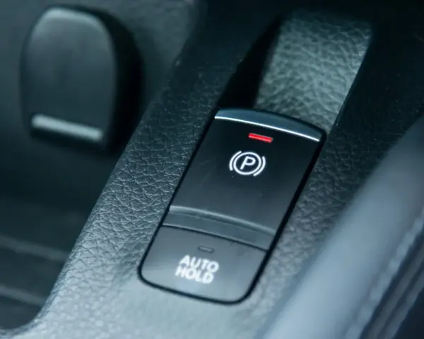 Pulsante freno a mano elettronico con spia rossa accesa e scritta "AUTO HOLD".