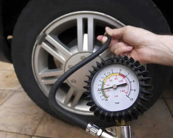 Controllo pressione pneumatici: un manometro collegato alla valvola di un'auto mostra la pressione attuale.