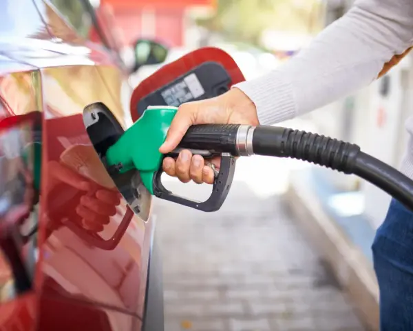 Mano che inserisce la pompa di benzina nel serbatoio di un'auto rossa. Attenzione a non mettere benzina nel diesel!