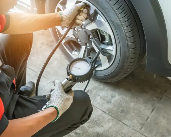 Meccanico controlla la pressione gomme, puntando a 3 bar per una guida sicura.