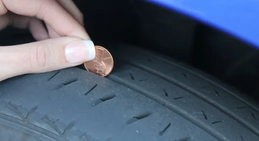 Dito si vede perché le gomme si consumano all'interno: una moneta viene inserita nel battistrada usurato di uno pneumatico.