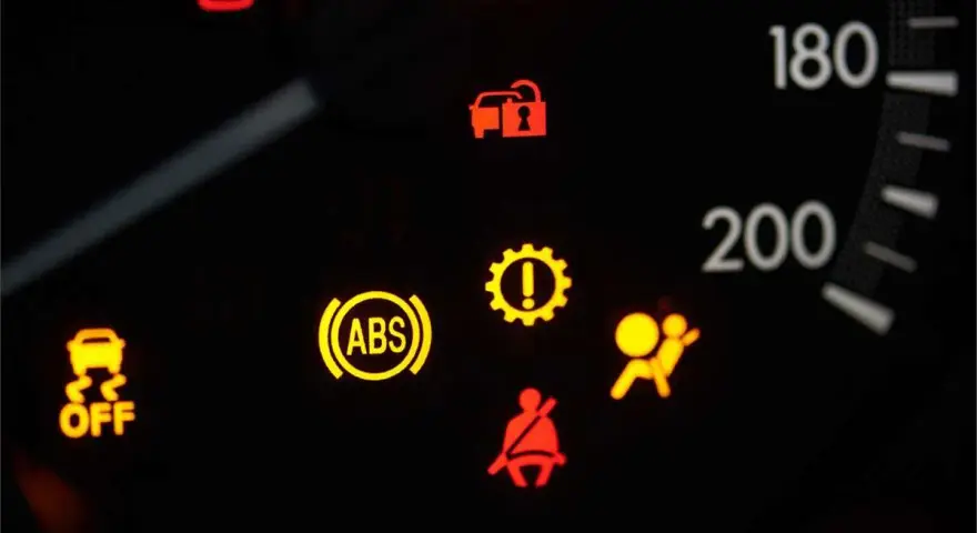 Cruscotto auto con spia ABS accesa fissa, insieme ad altre spie di avaria.