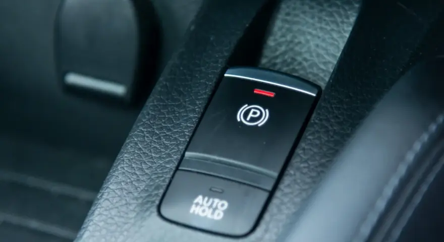 Pulsante freno a mano elettronico con spia rossa accesa e scritta "AUTO HOLD".