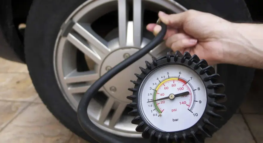 Controllo pressione pneumatici: un manometro collegato alla valvola di un'auto mostra la pressione attuale.