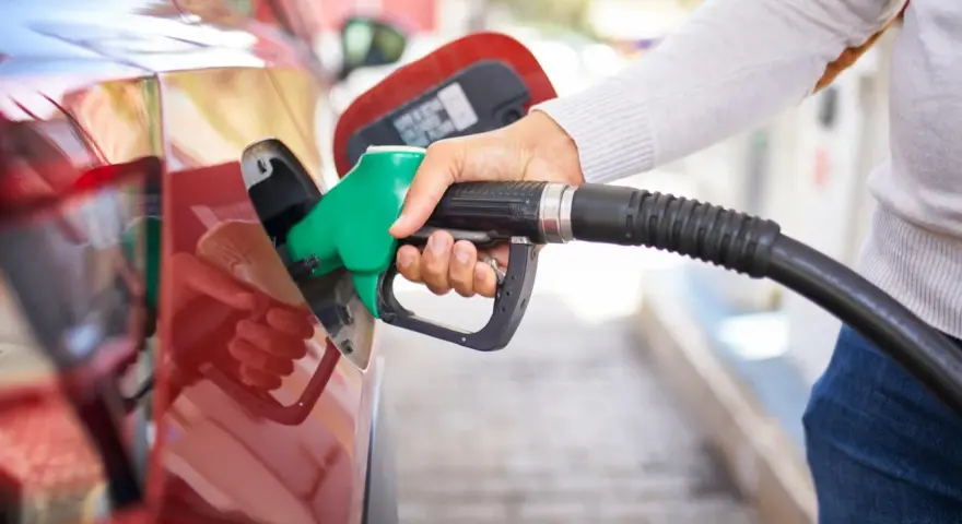 Mano che inserisce la pompa di benzina nel serbatoio di un'auto rossa. Attenzione a non mettere benzina nel diesel!