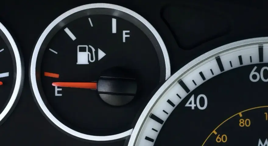 Cruscotto auto con indicatore carburante quasi vuoto, la spia pompa benzina è accesa.