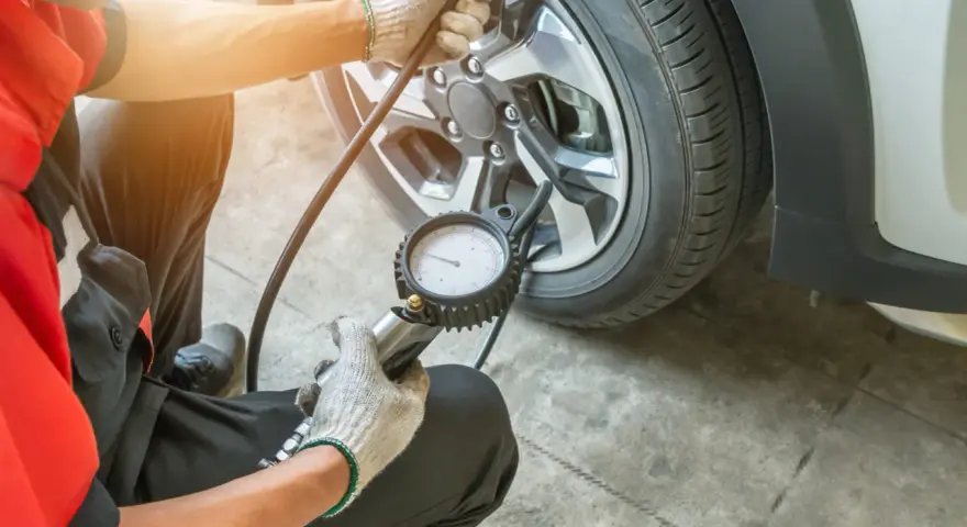 Meccanico controlla la pressione gomme, puntando a 3 bar per una guida sicura.