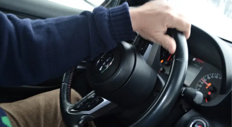 Mani sul volante, un promemoria su come guidare sulla neve: lentezza e dolcezza per affrontare le strade scivolose.