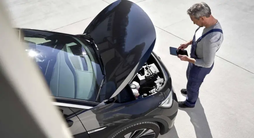 Meccanico con tablet controlla il motore dell'auto. Scopri quanto costa un tagliando auto per la tua vettura.