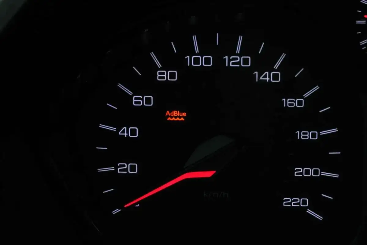 Cruscotto auto con spia AdBlue accesa, nonostante il rabbocco. Il tachimetro indica una velocità bassa.