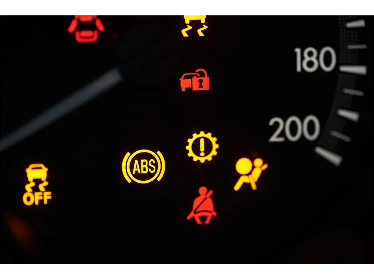 Cruscotto auto con spia ABS accesa fissa, insieme ad altre spie rosse e gialle.