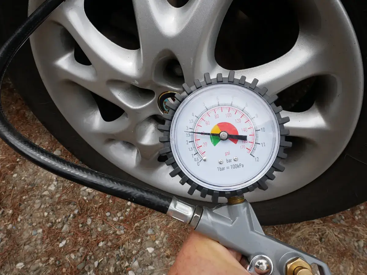 Controllo della pressione gomme auto estate: il manometro indica 2.5 bar, valore ottimale per viaggiare sicuri.