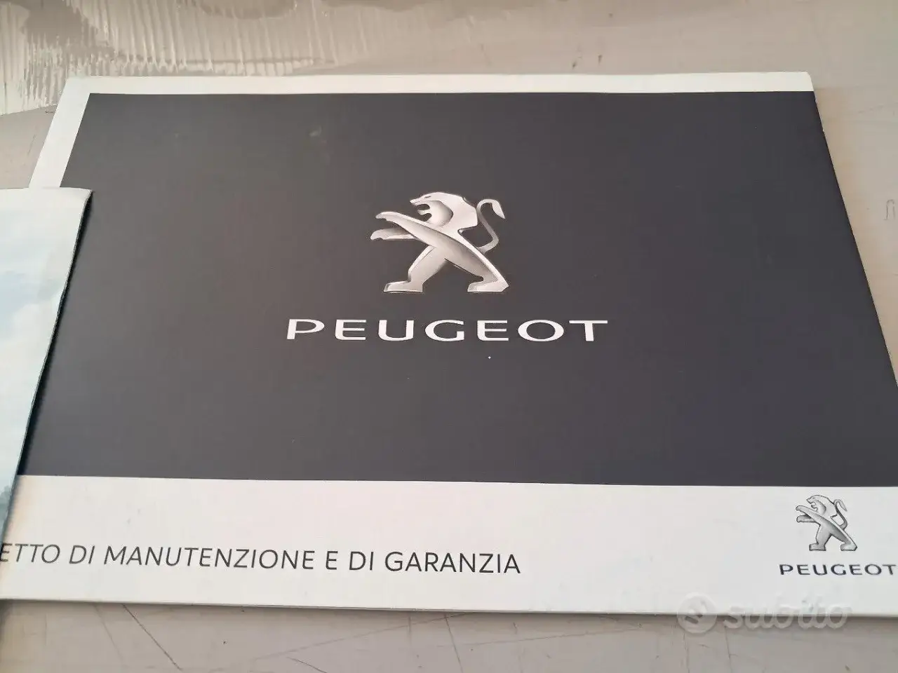 Libretto di manutenzione Peugeot 2008. Il leone Peugeot in rilievo sul coperchio grigio.