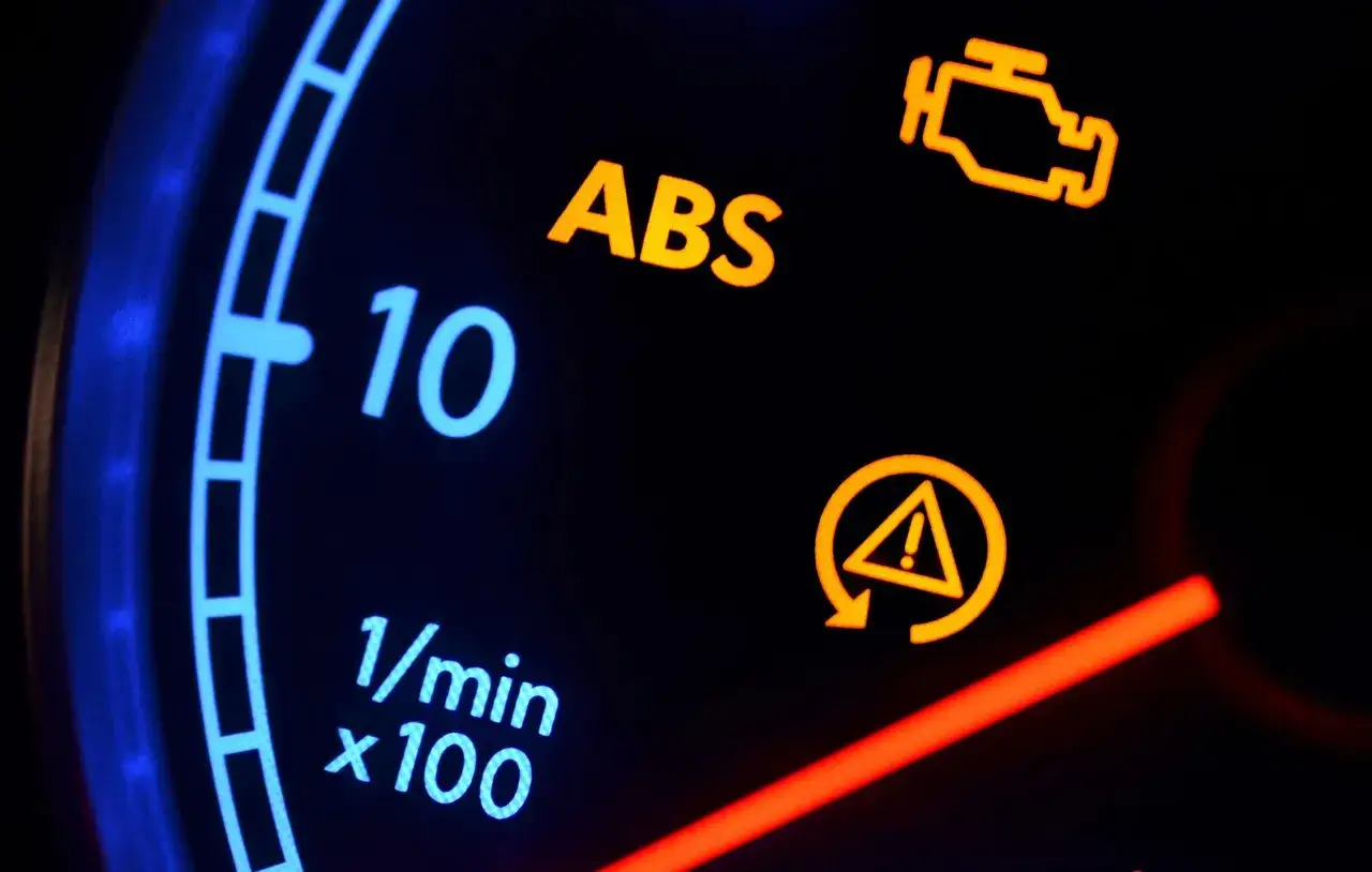 Cruscotto auto con spia ABS e freno a mano accese. Attenzione, problemi al sistema frenante o al motore.
