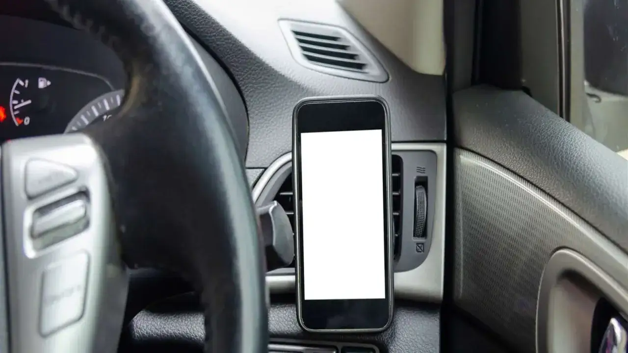 Cruscotto auto con cellulare agganciato, pronto per la navigazione. Attenzione al cellulare alla guida!